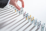 Hand placing domino into line of dominoes