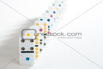 Line of colourful dominoes on white background