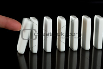 Finger pushing over dominoes