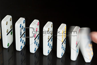 Finger pushing over colourful dominoes