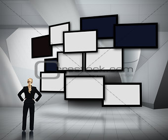 Group of blank screens on grey background with businesswoman looking up