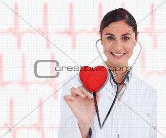 Doctor holding stethoscope up to red heart graphic