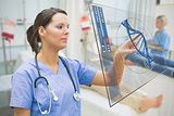 Nurse touching screen displaying blue DNA helix data