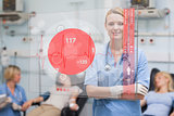 Smiling nurse standing behind red ECG display screen