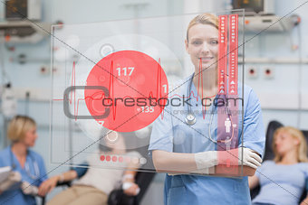 Smiling nurse standing behind red ECG display screen