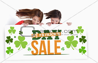 Girls holding placard with st patricks day sale text