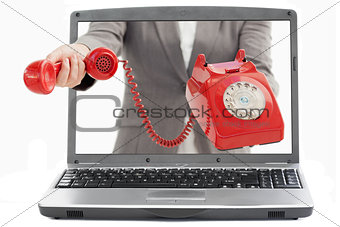 Businesswoman reaching out from laptop handing phone receiver
