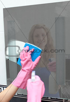 Woman wiping dirt from bathroom mirror