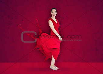 Happy asian woman with red dress turning to paint splatter