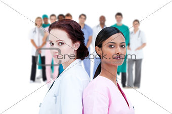 Serious doctor and nurse standing back to back
