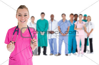 Smiling nurse with medical staff behind her