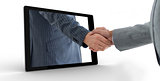 Businessman reaching out from tablet and shaking hands