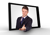 Businessman reaching out from tablet for a handshake