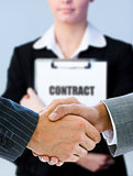 Businessmen shaking hands with contract behind them