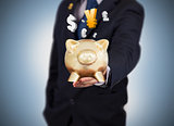 Businessman holding a gold piggy bank