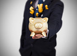 Businessman showing a gold piggy bank