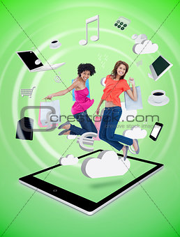 Two happy women jumping on a tablet pc