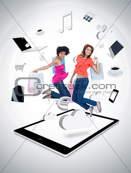 Two smiling women jumping on a tablet pc