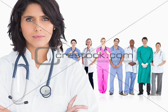 Woman doctor standing arms crossed in front of her team