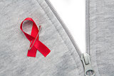 Aids awareness ribbon pinned on to grey zip jumper