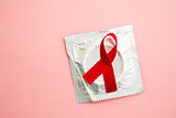 Red awareness ribbon lying on condom in wrapper