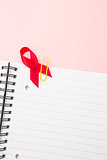 Awareness ribbon for aids clipped onto notepad