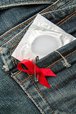 Condom in jeans pocket with red awareness ribbon pinned on