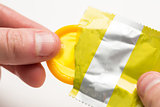 Hand pulling yellow condom from wrapper