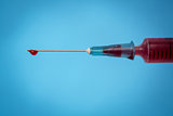 Drop of blood on needle of syringe