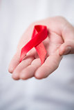 Man holding out red aids awareness ribbon