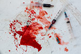 Three syringes lying on blood splatter