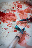 Two syringes lying on blood splatters