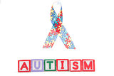 Autism awareness ribbon above letter blocks spelling autism