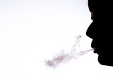 Silhouette of man blowing smoke