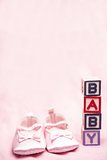 Baby girls pink booties beside blocks spelling baby
