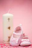 Pink baby booties with christening candle