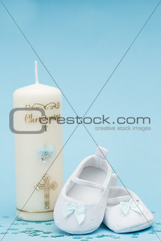 Baby booties with blue ribbon and christening candle