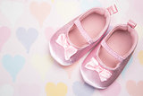 Baby pink booties on heart pattern background