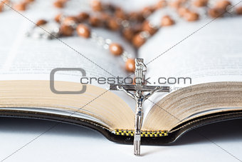 Cross of rosary beads resting against bible