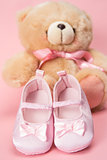 Pink baby booties and teddy bear
