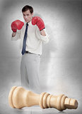 Businessman in boxing gloves with knocked over chess piece