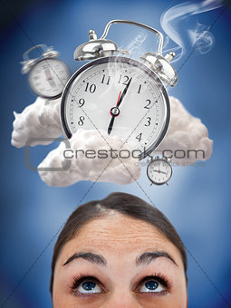 Woman looking up at ringing alarm clocks in clouds