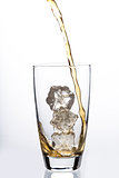 Liquid pouring into glass with ice cubes