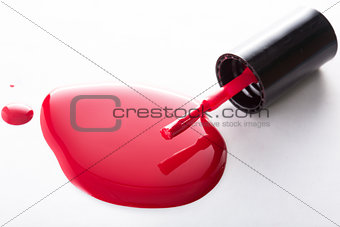 Puddle of red nail polish with brush