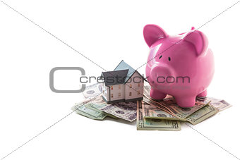 Piggy bank and miniature home resting on pile of dollars