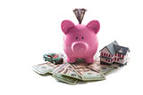 Piggy bank and toy car resting on pile of dollars with mini house
