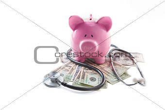 Piggy bank and stethoscope resting on pile of dollars