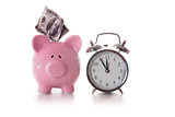 Alarm clock and piggy bank with dollar sticking out