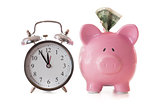 Dollar note sticking out of piggy bank beside alarm clock