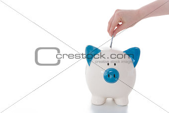 Hand putting money into piggy bank